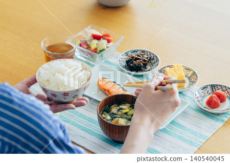 A young woman's hands as she eats breakfast at home A young woman's hands as she eats breakfast at home 140540045