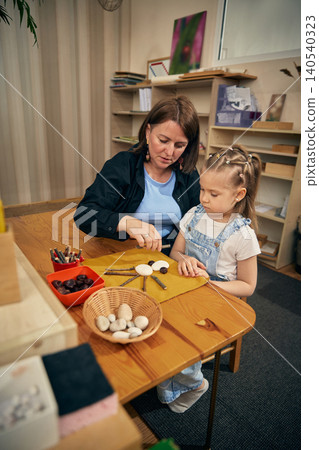 Natural material craft activity helping girl build focus in early learning classroom. Natural material craft activity helping girl build focus in early learning classroom. 140540323