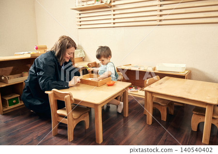 Sensory tray activity for toddler development in cozy early learning classroom. 140540402
