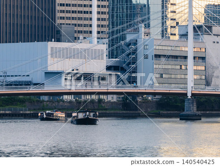 A houseboat sailing down the river at dusk, with the cityscape of skyscrapers in full view. A houseboat sailing down the river at dusk, with the cityscape of skyscrapers in full view. 140540425
