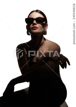 Woman in black sunglasses posing in dramatic shadow with elegant jewelry. Woman in black sunglasses posing in dramatic shadow with elegant jewelry. 140540616