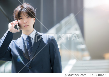 A close-up of the upper body of a handsome, middle-aged businessman walking up and down the stairs in his office, making a phone call on his smartphone. A close-up of the upper body of a handsome, middle-aged businessman walking up and down the stairs in his office, making a phone call on his smartphone. 140540646