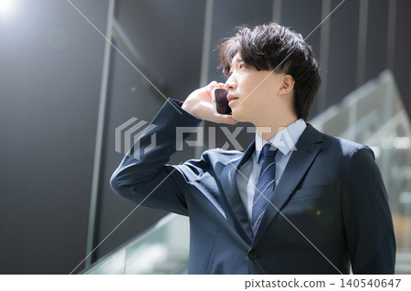 A handsome, middle-aged businessman walking up and down the stairs in the office while talking on his smartphone – a typical sales image. A handsome, middle-aged businessman walking up and down the stairs in the office while talking on his smartphone – a typical sales image. 140540647