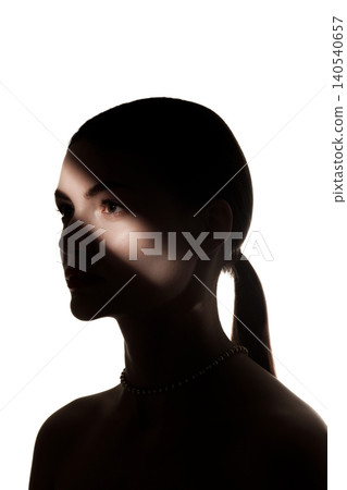 Profile beauty portrait of woman in silhouette with narrow light on face and white background. 140540657