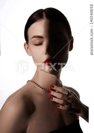 Front beauty portrait of woman with closed eyes and red manicure in split shadow lighting 140540658