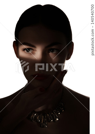 Close beauty portrait of serious woman with eye shadow strip and dark jewelry. 140540700