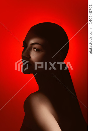 Side beauty portrait of serene woman in dark silhouette on red background. Side beauty portrait of serene woman in dark silhouette on red background. 140540701