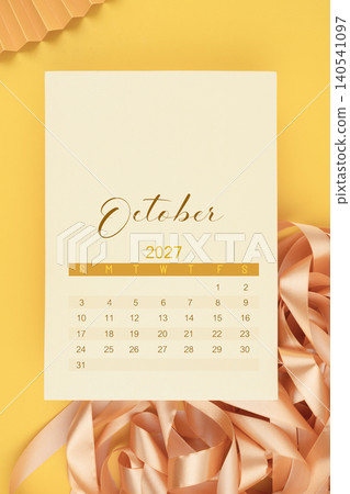 October 2027 calendar page with yellow ribbon on yellow background. October 2027 calendar page with yellow ribbon on yellow background. 140541097