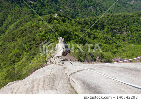 Steep granite cliff with climbing rope on Suraksan mountain ridge path Steep granite cliff with climbing rope on Suraksan mountain ridge path 140542298