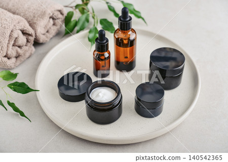 Natural skincare and beauty treatment concept with amber glass cosmetic containers arranged on a round tray. Natural skincare and beauty treatment concept with amber glass cosmetic containers arranged on a round tray. 140542365