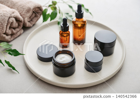 Natural skincare and beauty treatment concept with amber glass cosmetic containers arranged on a round tray. 140542366