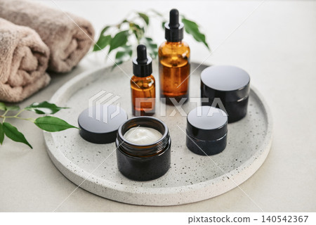 Natural skincare and beauty treatment concept with amber glass cosmetic containers arranged on a round tray. Natural skincare and beauty treatment concept with amber glass cosmetic containers arranged on a round tray. 140542367