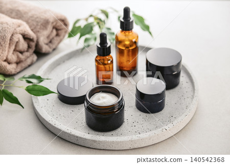 Natural skincare and beauty treatment concept with amber glass cosmetic containers arranged on a round tray. Natural skincare and beauty treatment concept with amber glass cosmetic containers arranged on a round tray. 140542368
