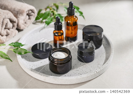 Natural skincare and beauty treatment concept with amber glass cosmetic containers arranged on a round tray. 140542369
