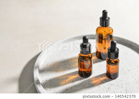 Natural skincare and beauty treatment concept with amber glass cosmetic containers arranged on a round tray. Natural skincare and beauty treatment concept with amber glass cosmetic containers arranged on a round tray. 140542370