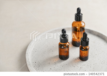 Natural skincare and beauty treatment concept with amber glass cosmetic containers arranged on a round tray. Natural skincare and beauty treatment concept with amber glass cosmetic containers arranged on a round tray. 140542371