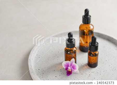 Natural skincare and beauty treatment concept with amber glass cosmetic containers arranged on a round tray. Natural skincare and beauty treatment concept with amber glass cosmetic containers arranged on a round tray. 140542373