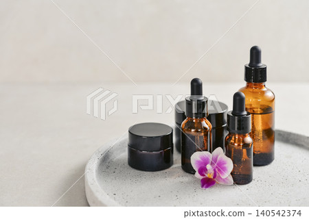 Natural skincare and beauty treatment concept with amber glass cosmetic containers arranged on a round tray. 140542374