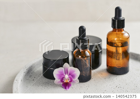 Natural skincare and beauty treatment concept with amber glass cosmetic containers arranged on a round tray. Natural skincare and beauty treatment concept with amber glass cosmetic containers arranged on a round tray. 140542375
