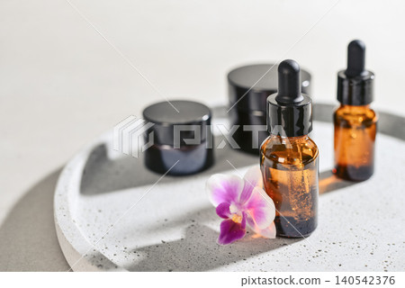 Natural skincare and beauty treatment concept with amber glass cosmetic containers arranged on a round tray. Natural skincare and beauty treatment concept with amber glass cosmetic containers arranged on a round tray. 140542376