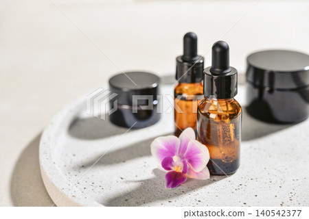Natural skincare and beauty treatment concept with amber glass cosmetic containers arranged on a round tray. 140542377
