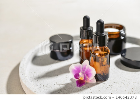 Natural skincare and beauty treatment concept with amber glass cosmetic containers arranged on a round tray. Natural skincare and beauty treatment concept with amber glass cosmetic containers arranged on a round tray. 140542378