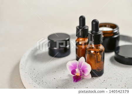 Natural skincare and beauty treatment concept with amber glass cosmetic containers arranged on a round tray. Natural skincare and beauty treatment concept with amber glass cosmetic containers arranged on a round tray. 140542379