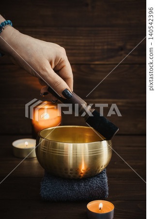 A close-up wellness scene showing a female hand gently playing a singing bowl with a mallet A close-up wellness scene showing a female hand gently playing a singing bowl with a mallet 140542396