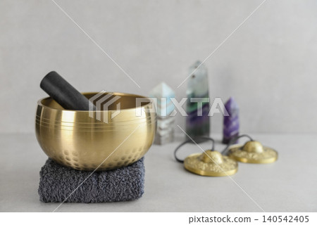 A bright, minimal wellness composition featuring a singing bowl surrounded by folded towels, tingsha bells, and healing crystals A bright, minimal wellness composition featuring a singing bowl surrounded by folded towels, tingsha bells, and healing crystals 140542405