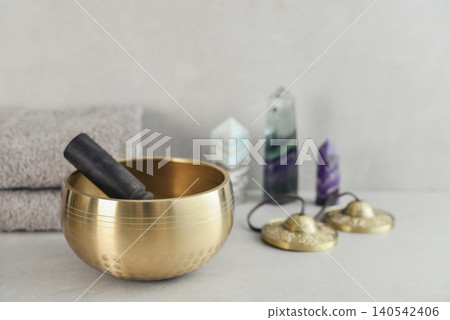 A bright, minimal wellness composition featuring a singing bowl surrounded by folded towels, tingsha bells, and healing crystals A bright, minimal wellness composition featuring a singing bowl surrounded by folded towels, tingsha bells, and healing crystals 140542406