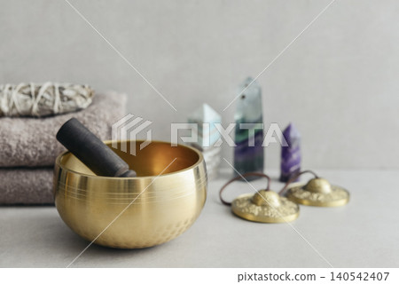 A bright, minimal wellness composition featuring a singing bowl surrounded by folded towels, tingsha bells, and healing crystals A bright, minimal wellness composition featuring a singing bowl surrounded by folded towels, tingsha bells, and healing crystals 140542407