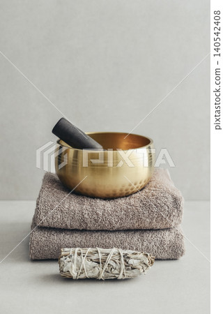 A bright, minimal wellness composition featuring a singing bowl surrounded by folded towels, tingsha bells, and healing crystals A bright, minimal wellness composition featuring a singing bowl surrounded by folded towels, tingsha bells, and healing crystals 140542408