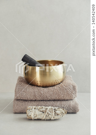 A bright, minimal wellness composition featuring a singing bowl surrounded by folded towels, tingsha bells, and healing crystals A bright, minimal wellness composition featuring a singing bowl surrounded by folded towels, tingsha bells, and healing crystals 140542409