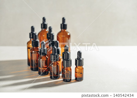 Amber glass dropper bottles of different sizes arranged in ascending order from smallest to largest on light background. Amber glass dropper bottles of different sizes arranged in ascending order from smallest to largest on light background. 140542434
