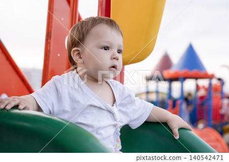 Portrait of a serious little toddler playing on a colorful outdoor playground Portrait of a serious little toddler playing on a colorful outdoor playground 140542471