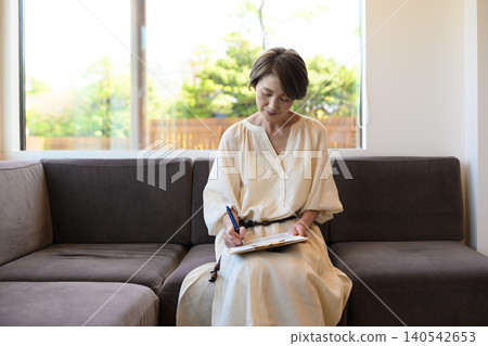 Japanese woman writing on a sofa Japanese woman writing on a sofa 140542653