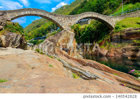 Ancient double arch stone Roman bridge (Ponte dei Salti) over the clear water of the Verzasca river in Lavertezzo ,Verzasca Valley, Ticino Canton, Switzerland Ancient double arch stone Roman bridge (Ponte dei Salti) over the clear water of the Verzasca river in Lavertezzo ,Verzasca Valley, Ticino Canton, Switzerland 140542828