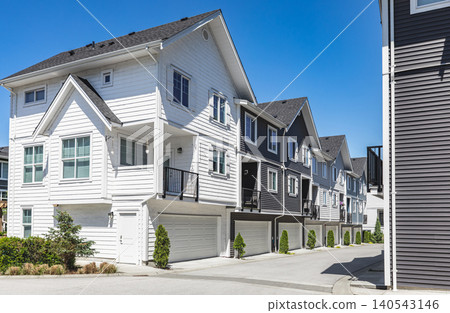 New townhouses in residential comfortable neighborhood on a sunny day. Real Estate Exterior Front Homes with garages in suburbs North America. Modern apartment buildings. Housing development New townhouses in residential comfortable neighborhood on a sunny day. Real Estate Exterior Front Homes with garages in suburbs North America. Modern apartment buildings. Housing development 140543146
