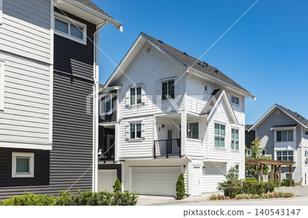 New townhouses in residential comfortable neighborhood on a sunny day. Real Estate Exterior Front Homes with garages in suburbs North America. Modern apartment buildings. Housing development New townhouses in residential comfortable neighborhood on a sunny day. Real Estate Exterior Front Homes with garages in suburbs North America. Modern apartment buildings. Housing development 140543147