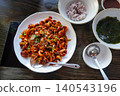 Spicy stir-fried webfoot octopus jukkumi bokkeum with rice and seaweed soup on a wooden table 140543196