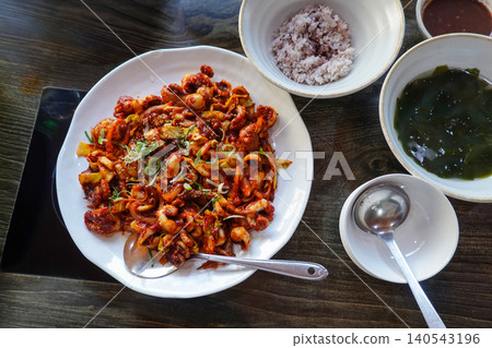 Spicy stir-fried webfoot octopus jukkumi bokkeum with rice and seaweed soup on a wooden table Spicy stir-fried webfoot octopus jukkumi bokkeum with rice and seaweed soup on a wooden table 140543196