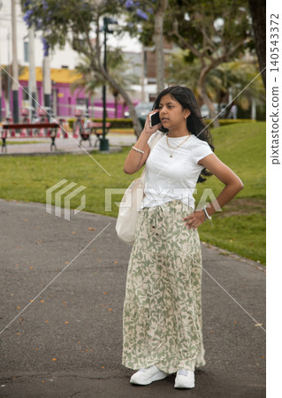 A young girl is talking on her cell phone while walking down a sidewalk 140543372