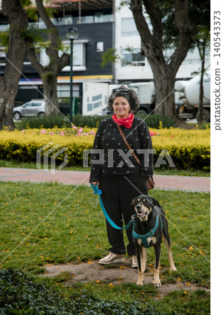 A woman and her dog are walking in a park A woman and her dog are walking in a park 140543373