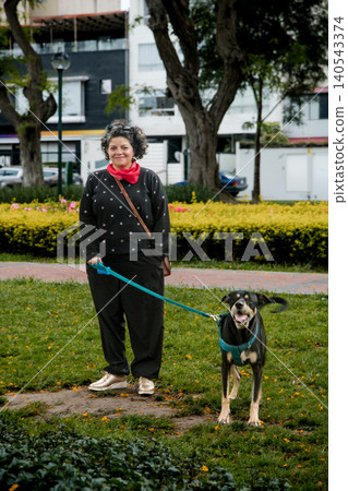 A woman and her dog are walking in a park A woman and her dog are walking in a park 140543374