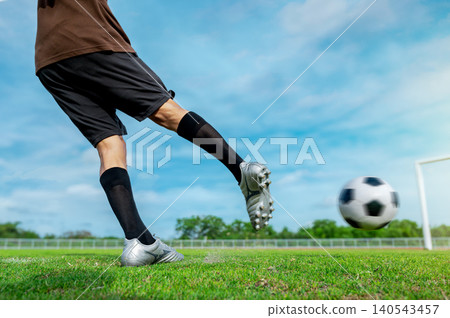 Medium Shot of Powerful Soccer Player Kicking Football: Intense Striker Shooting a Goal on Green Field Medium Shot of Powerful Soccer Player Kicking Football: Intense Striker Shooting a Goal on Green Field 140543457