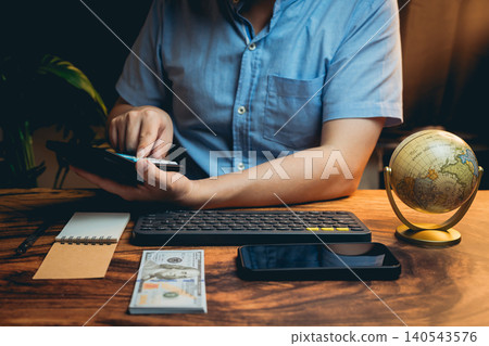 Hands of Business Professional Working on Tablet with Smartphone and Globe on Wooden Desk in Modern Office 140543576