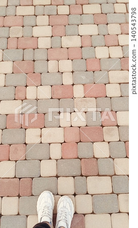 Top View of Feet in White Sneakers on Colorful Geometric Paving Stones - POV Lifestyle Shot Top View of Feet in White Sneakers on Colorful Geometric Paving Stones - POV Lifestyle Shot 140543798