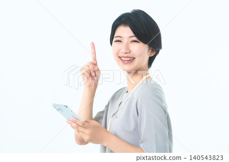 A young woman with a smile, holding her smartphone and raising her index finger. A young woman with a smile, holding her smartphone and raising her index finger. 140543823