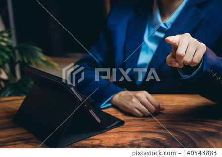 Business Professional Pointing at Tablet with Focused Expression in Modern Office Setting 140543883