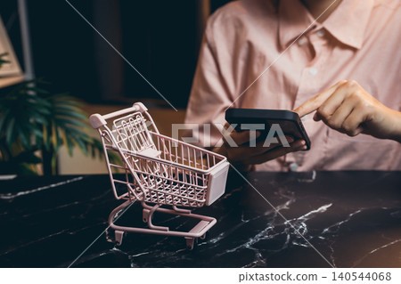 Small Shopping Cart and Mobile Phone in Modern Workspace with Marble Table and Soft Lighting Small Shopping Cart and Mobile Phone in Modern Workspace with Marble Table and Soft Lighting 140544068